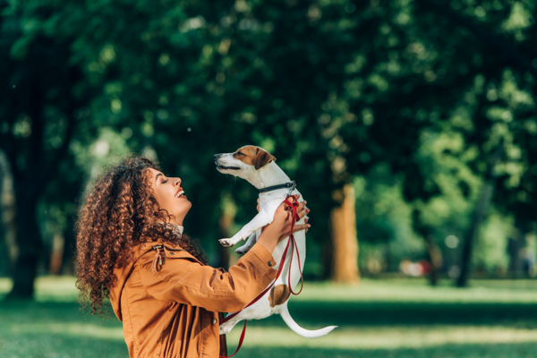 Proud woman holds up her well-trained dog on a leash, showcasing obedience and improved behavior