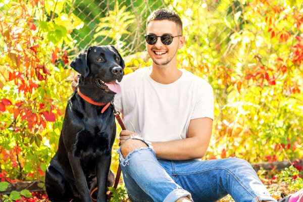 Heartwarming moment of a man and his trained Labrador sitting together, highlighting the bond between owner and dog